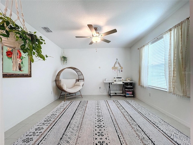 unfurnished room featuring ceiling fan, light tile patterned floors, and a textured ceiling