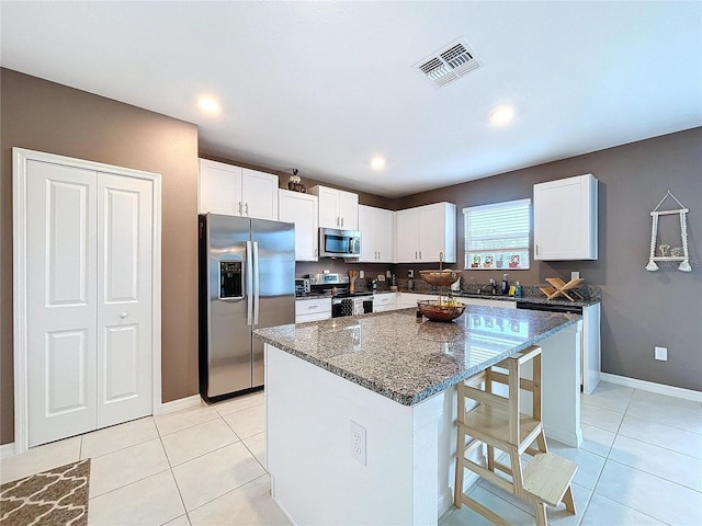 kitchen with dark stone countertops, white cabinetry, a center island, and appliances with stainless steel finishes