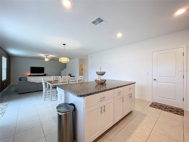 kitchen with a center island, white cabinets, hanging light fixtures, ceiling fan, and light tile patterned floors