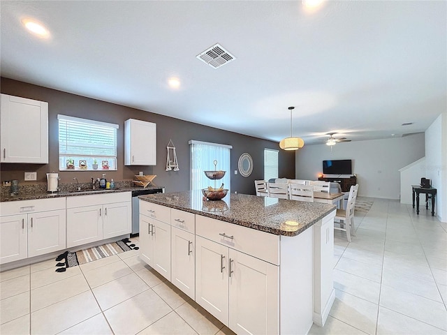 kitchen with ceiling fan, white cabinets, decorative light fixtures, and a kitchen island