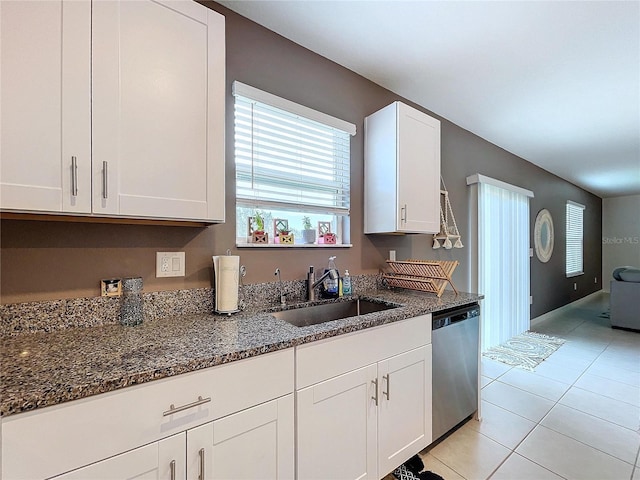 kitchen with stainless steel dishwasher, white cabinetry, sink, and dark stone counters