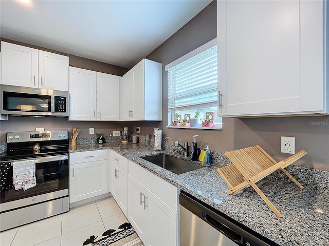 kitchen with white cabinets, stone countertops, light tile patterned floors, and appliances with stainless steel finishes