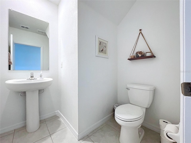 bathroom with toilet, tile patterned floors, lofted ceiling, and sink