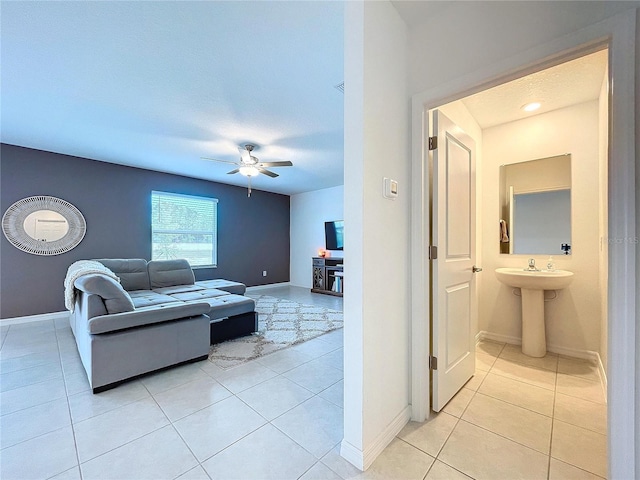 tiled living room with ceiling fan and sink