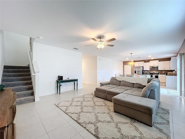 living room featuring ceiling fan, light tile patterned flooring, and a textured ceiling