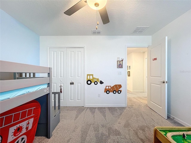 bedroom featuring ceiling fan, light colored carpet, a textured ceiling, and a closet