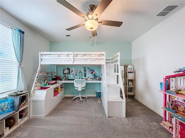 carpeted bedroom featuring ceiling fan and a textured ceiling