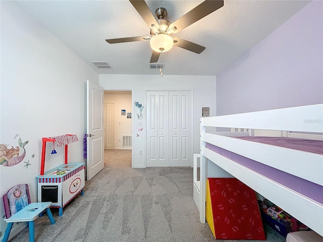 bedroom featuring a textured ceiling, a closet, light colored carpet, and ceiling fan