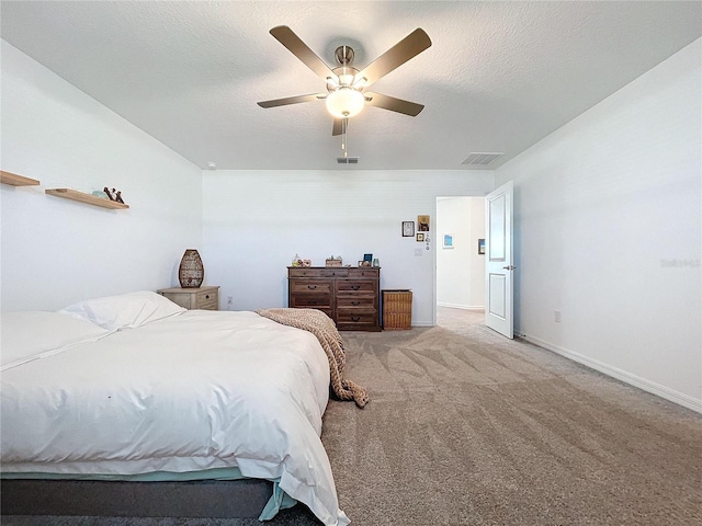 bedroom with ceiling fan, light colored carpet, and a textured ceiling