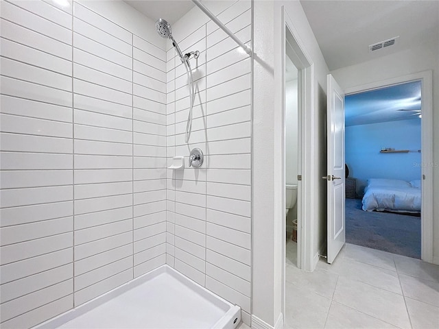 bathroom featuring toilet, a tile shower, and tile patterned floors