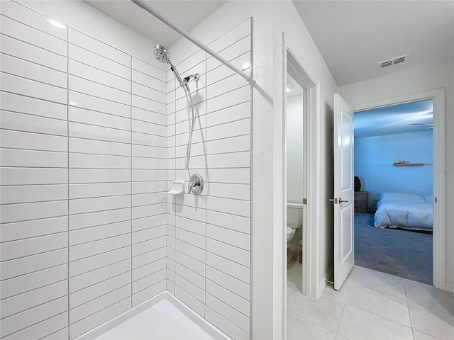 bathroom featuring tile patterned floors, toilet, and a tile shower