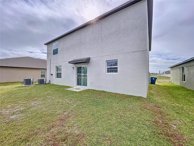 rear view of property featuring cooling unit and a lawn