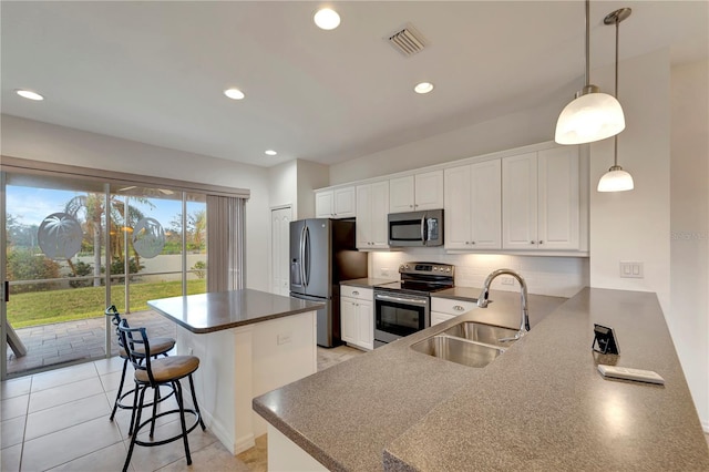 kitchen featuring white cabinetry, appliances with stainless steel finishes, hanging light fixtures, sink, and kitchen peninsula