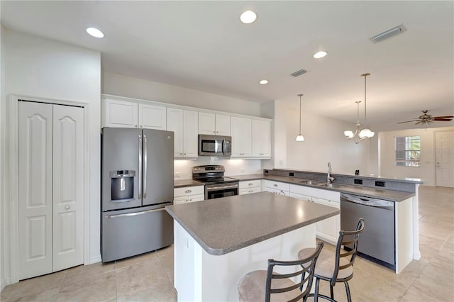 kitchen featuring kitchen peninsula, white cabinets, a breakfast bar, and appliances with stainless steel finishes