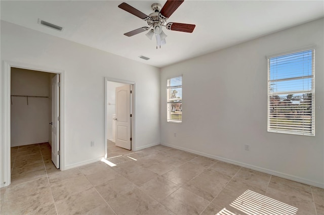 unfurnished bedroom with ceiling fan, a closet, and a walk in closet