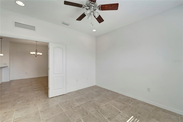 spare room featuring ceiling fan with notable chandelier