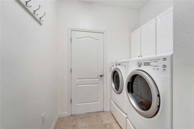 laundry area featuring washer and clothes dryer, cabinets, and light tile patterned floors