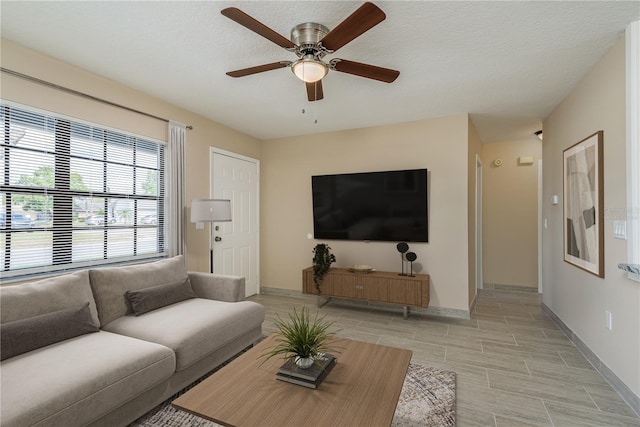 living room with ceiling fan and a textured ceiling