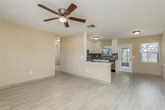 unfurnished living room with a textured ceiling, light hardwood / wood-style flooring, sink, and ceiling fan