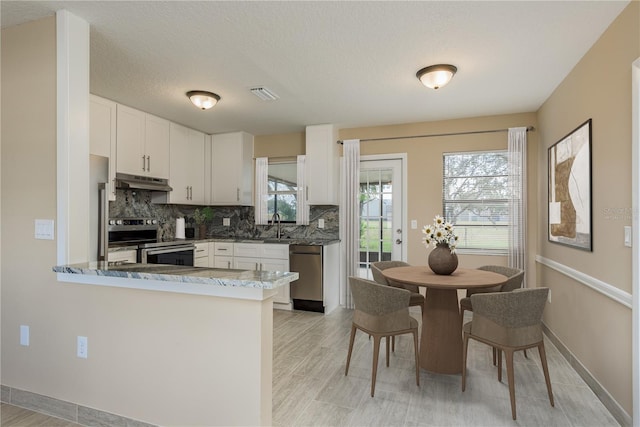 kitchen with white cabinetry, kitchen peninsula, appliances with stainless steel finishes, a textured ceiling, and decorative backsplash