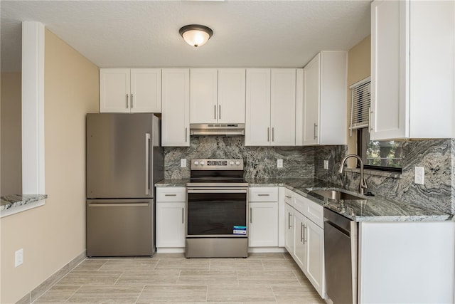 kitchen featuring tasteful backsplash, stainless steel appliances, dark stone counters, white cabinetry, and sink