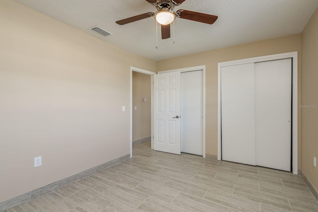 unfurnished bedroom with multiple closets, a textured ceiling, and ceiling fan