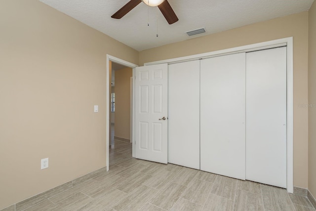 unfurnished bedroom with a textured ceiling, ceiling fan, and a closet