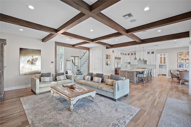 living room featuring beamed ceiling, light hardwood / wood-style floors, plenty of natural light, and coffered ceiling