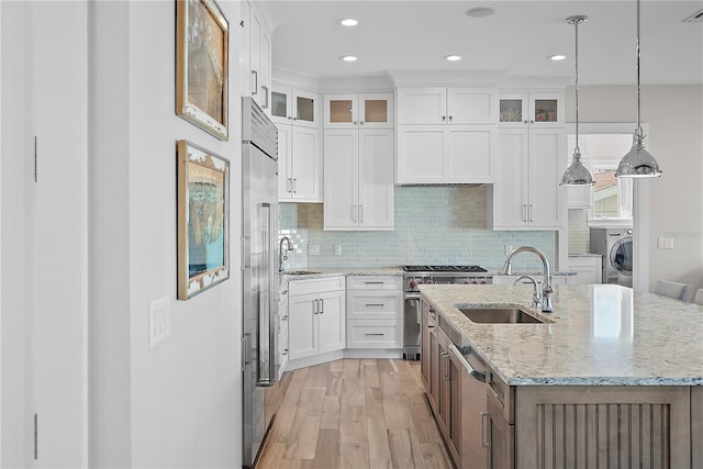 kitchen with white cabinets, a center island with sink, sink, and hanging light fixtures