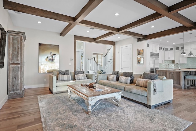 living room with beam ceiling, sink, light hardwood / wood-style floors, and coffered ceiling