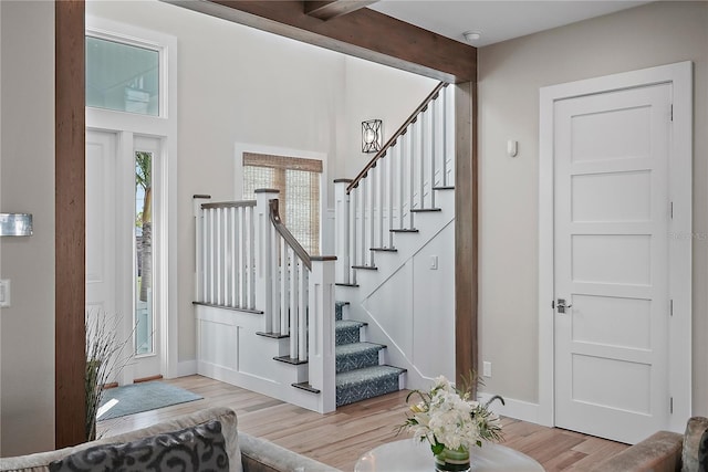 entryway with beam ceiling and light wood-type flooring