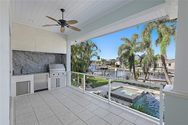 view of patio / terrace with an outdoor kitchen, a water view, sink, ceiling fan, and area for grilling