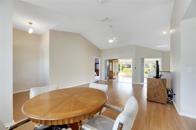 dining room with light hardwood / wood-style floors, ceiling fan, and vaulted ceiling