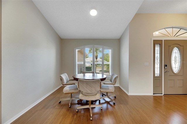 dining space with a textured ceiling and light hardwood / wood-style flooring