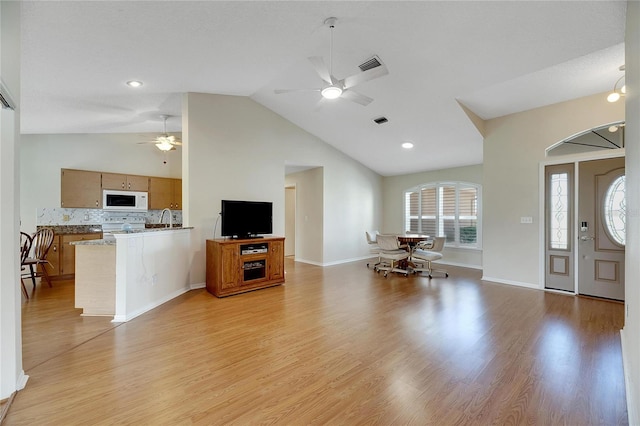 living room with ceiling fan, sink, light wood-type flooring, and lofted ceiling