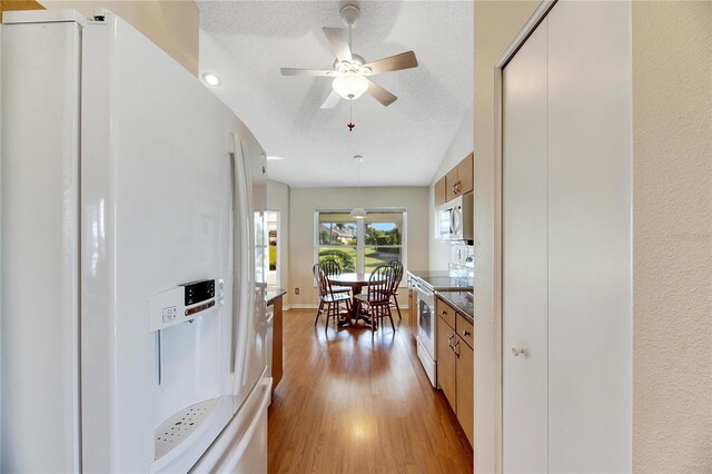 719 Winterbrooke Way, Sun City Center, FL 33573 - kitchen featuring white appliances, light wood-style flooring, a ceiling fan, brown cabinets, and a textured ceiling