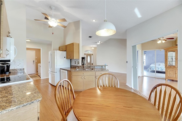 dining space featuring a textured ceiling, light wood-type flooring, sink, and high vaulted ceiling