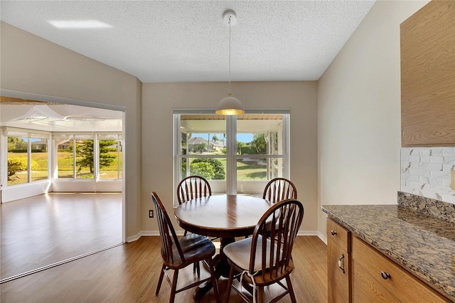 dining area with a textured ceiling, hardwood / wood-style flooring, and a healthy amount of sunlight