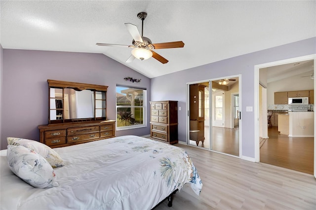 bedroom featuring light hardwood / wood-style floors, ceiling fan, a textured ceiling, and vaulted ceiling