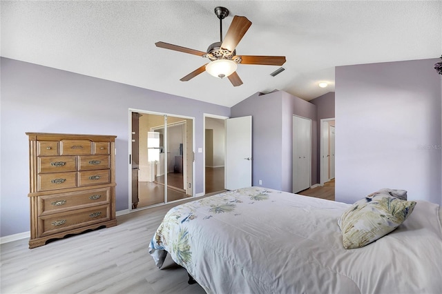 bedroom with ensuite bath, lofted ceiling, a textured ceiling, ceiling fan, and light wood-type flooring