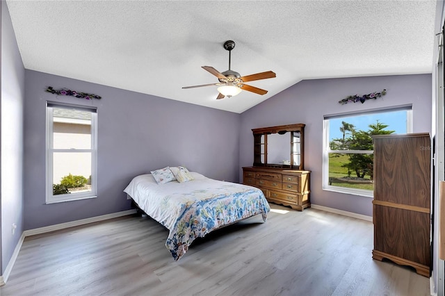 bedroom with ceiling fan, multiple windows, light hardwood / wood-style flooring, and vaulted ceiling