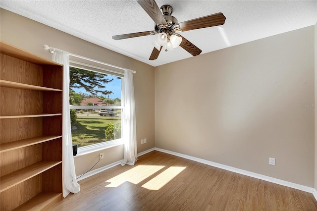 spare room with ceiling fan, a textured ceiling, and light wood-type flooring