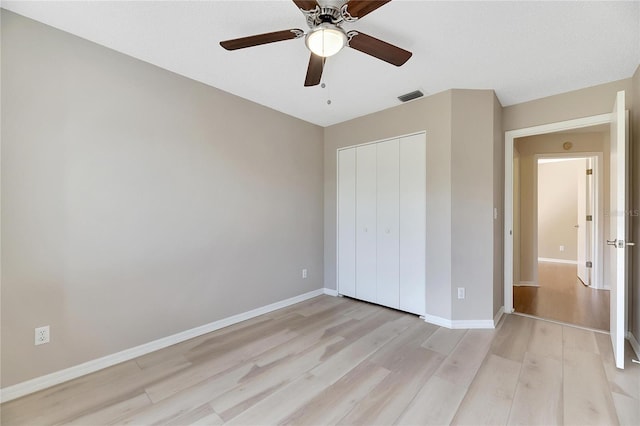 unfurnished bedroom featuring ceiling fan, a closet, and light wood-type flooring