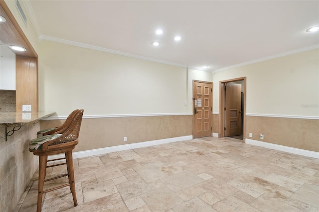 empty room featuring bar area and crown molding