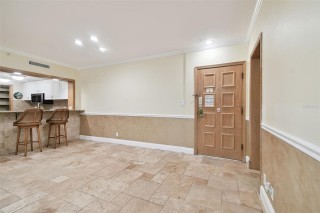 interior space featuring crown molding, a kitchen breakfast bar, and white cabinets