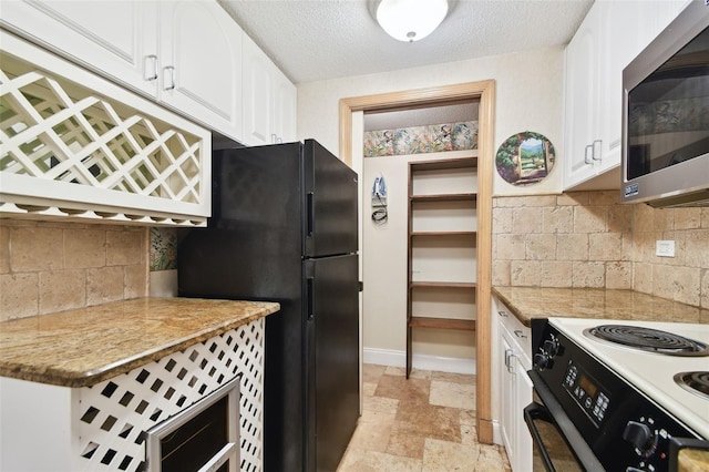 kitchen with black refrigerator, light stone countertops, decorative backsplash, and white cabinets