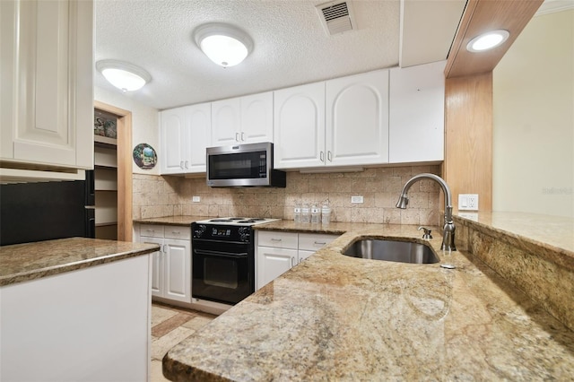 kitchen with black electric range, tasteful backsplash, light stone counters, sink, and white cabinets