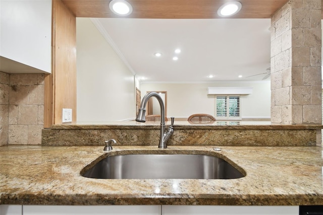 kitchen featuring ornamental molding, sink, and stone countertops