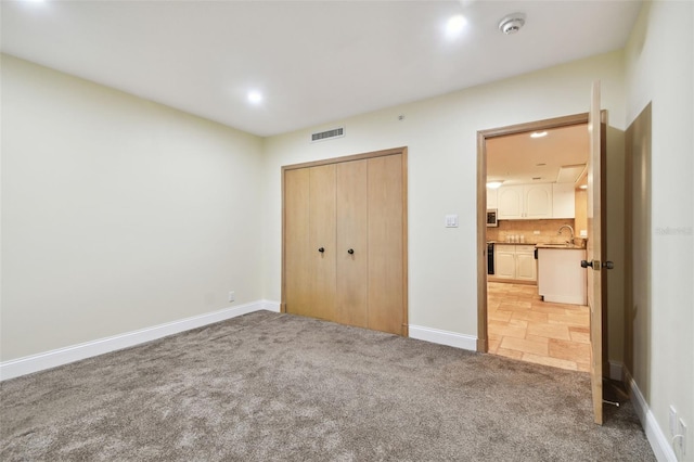 unfurnished bedroom with a closet, sink, and carpet floors