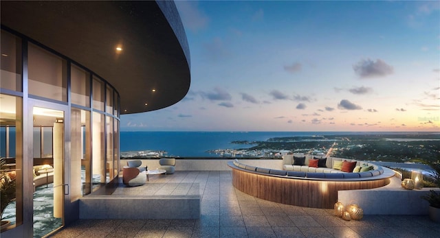 balcony at dusk featuring a water view